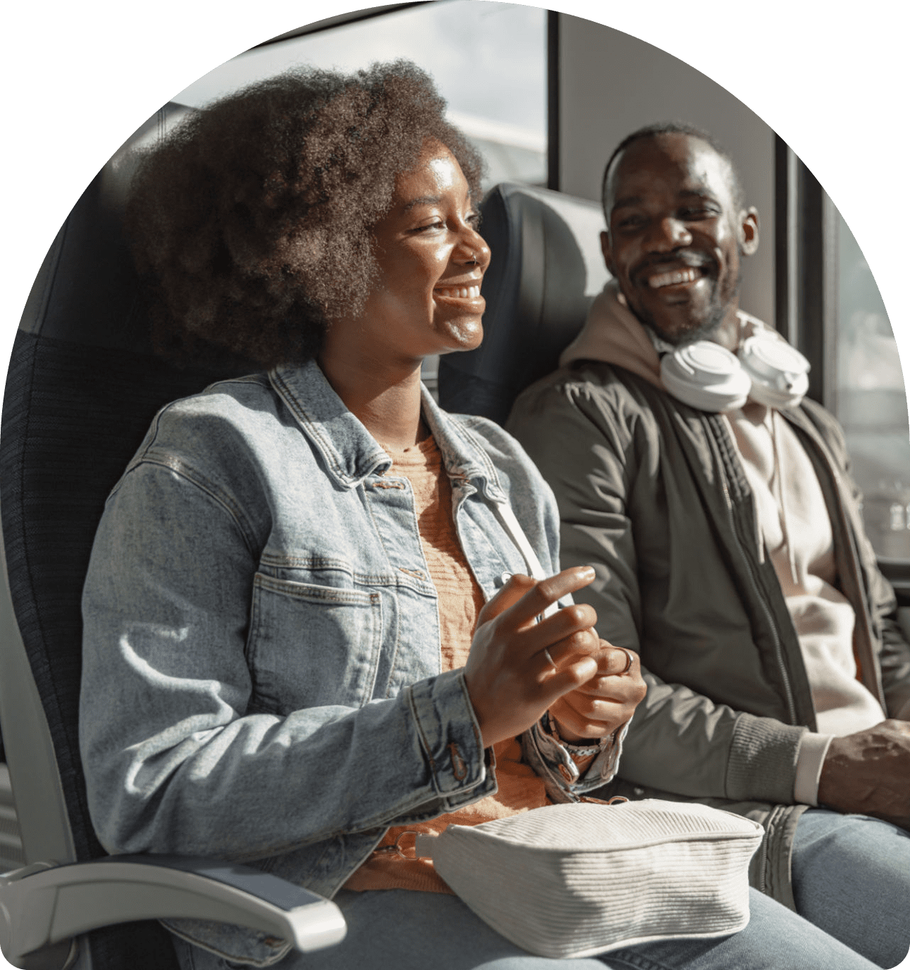 Two people smiling and talking on train.