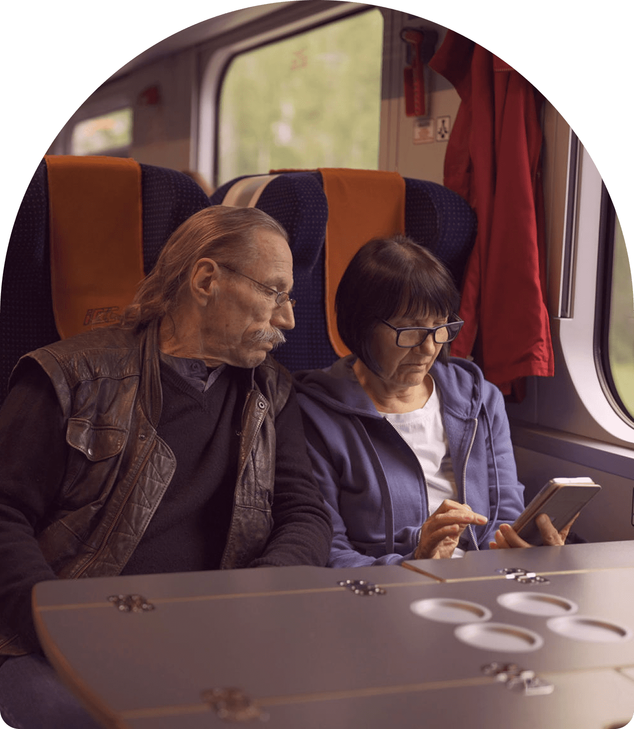 Couple on train looking at smartphone screen.